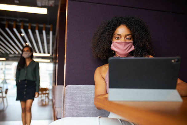Empresária vestindo máscara trabalhando em cubículo socialmente distante no escritório durante a pandemia de saúde - Foto, Imagem