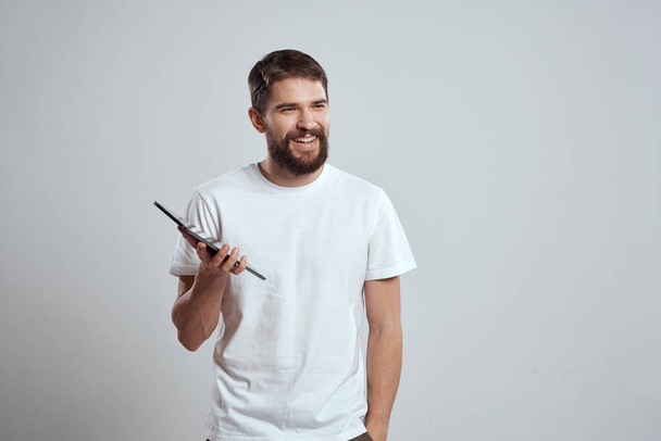 Ein Mann in einem weißen T-Shirt mit einem Tablet in der Hand - Foto, Bild
