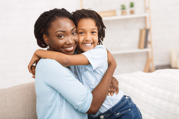 zwart moeder en dochter knuffelen thuis - Foto, afbeelding