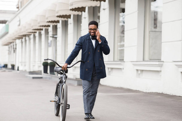 Beau homme d'affaires parlant au téléphone tenant son vélo - Photo, image