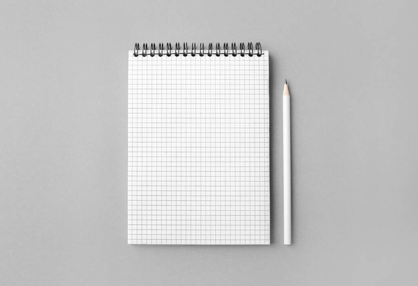 Blanco spiraal notitieboekje en wit potlood op grijze achtergrond. Bovenaanzicht. - Foto, afbeelding
