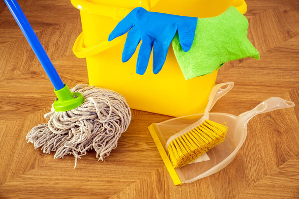 Чистка підлоги мопедом і синіми рукавичками на жовтому відрі. Прибиральник створить гігієну на будинку
 - Фото, зображення
