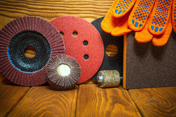 Великий набір абразивних інструментів і помаранчевих робочих рукавичок на старовинних дерев'яних дошках майстра використовується для шліфування предметів. Інструмент готовий до роботи
 - Фото, зображення