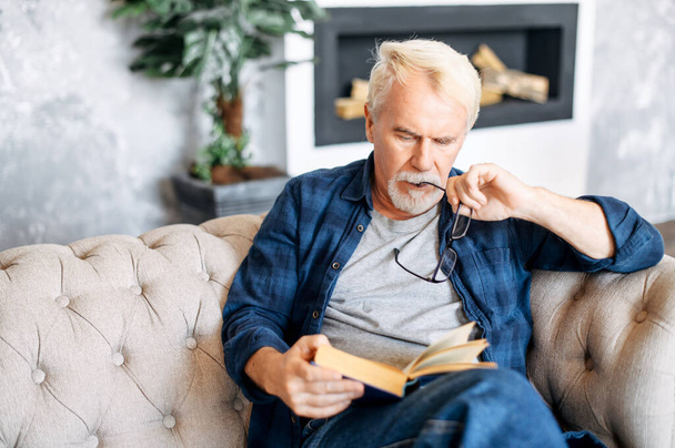 Mature man in eyeglasses is reading a book - Foto, Imagen