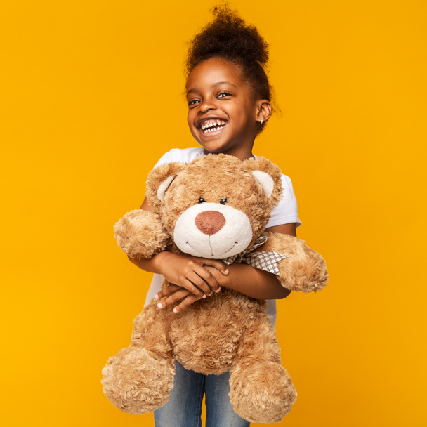 Cute black girl embracing big toy teddy bear - Foto, Imagen