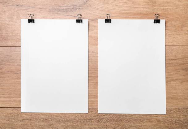 Blank sheets with binder clips on wooden background. Top view. - Photo, Image