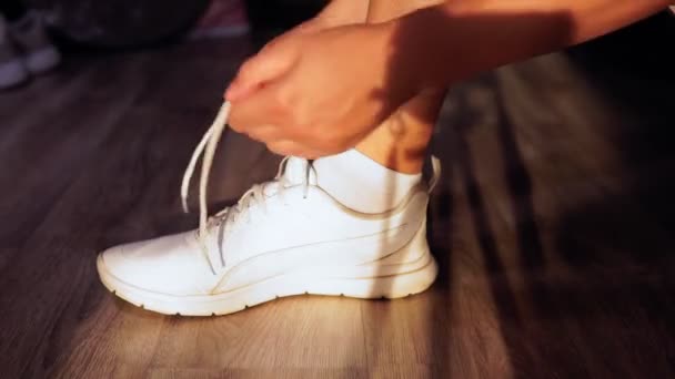 χέρι άνθρωπος δένει μέχρι κορδόνια σε λευκό sneakers στο σπίτι νωρίς το πρωί - Πλάνα, βίντεο