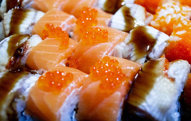 Comida japonesa para llevar: rollos de arroz con salmón y caviar, y rollos con salsa de anguila y teriyaki. Fondo alimenticio. Enfoque selectivo. - Foto, Imagen