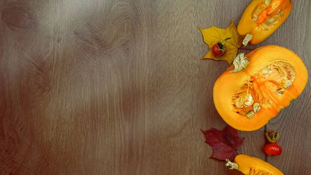 Autumn harvest composition with Cut pumpkin and maple leaves on wooden background . High quality photo - Valokuva, kuva