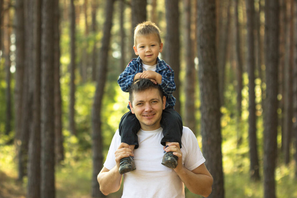 Šťastný mladý otec se svým synem baví venku. Štěstí a harmonie v rodinném životě. - Fotografie, Obrázek