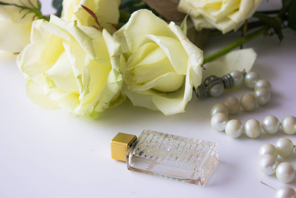 roses blanches et une bouteille de parfum sur un fond clair. - Photo, image