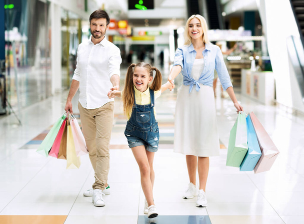 Οικογένεια των τριών που μεταφέρουν τσάντες Shopper μετά τα ψώνια στο εμπορικό κέντρο - Φωτογραφία, εικόνα