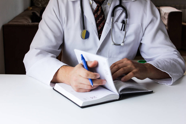 Male doctor writing in notebook. Young caucasian male medical professional. - Photo, Image