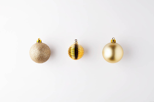 Trendy metallic gold Christmas shiny and matte balls on white background with copy space.New Year greeting card.Minimal christmas concept idea.Flat lay,top view - Foto, Bild
