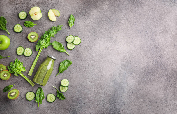 Fresh green healthy organic juice in glass bottle on stone background. Top view. Copy space. - 写真・画像