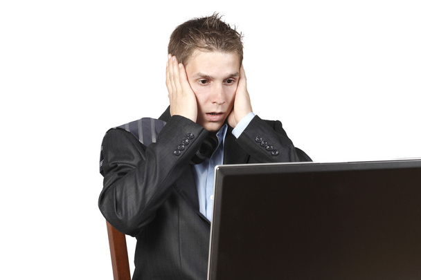 Empresário sentado ao lado de um laptop e ficou horrorizado olha para
 - Foto, Imagem