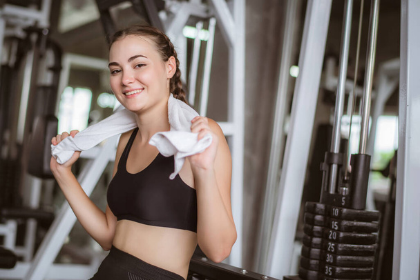 Young attractive using towel to wipe the sweat. Relaxation after hard workout in gym. - Photo, Image