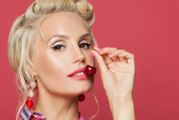 Young pin-up woman with make up eating cherry, close up portrait - Fotoğraf, Görsel