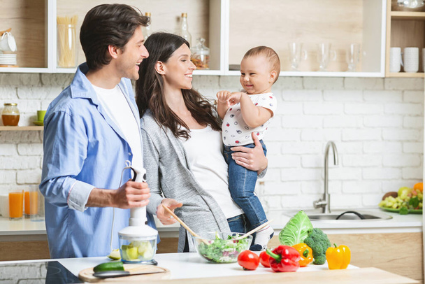 Happy family of three cooking together at kitchen - Photo, Image