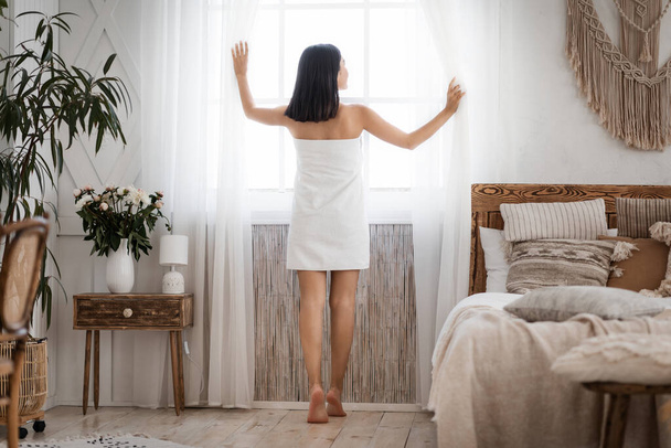 Vékony ázsiai nő néz be az ablakon a hálószobában - Fotó, kép