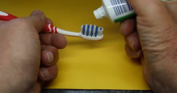 Зубная паста наносится на зубную щетку для чистки зубов - Кадры, видео