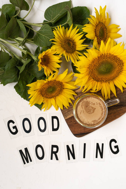 Hyvää huomenta. Kimppu suuria auringonkukkia ja kuumaa kahvia. Auringonkukka järjestely tasainen lay tyyli taustalla valkoinen - Valokuva, kuva