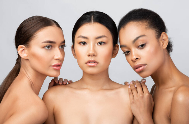 Три красиві багатоетнічні моделі дівчата позують сорочку над сірим тлом
 - Фото, зображення