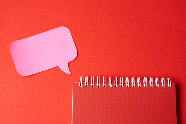 Notepad with pink sticky note on red background top view Copy Space - 写真・画像