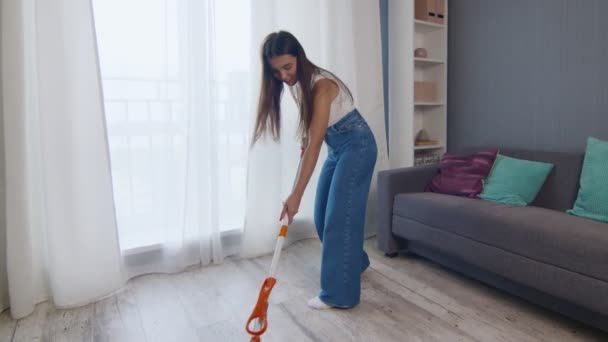 Femme gaie nettoyer la maison tout en chantant en utilisant la serpillière comme microphone. - Séquence, vidéo
