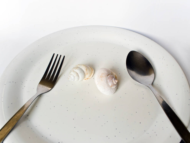 Skorupa ślimaka lądowego w naczyniu z łyżką i widelcem - Zdjęcie, obraz