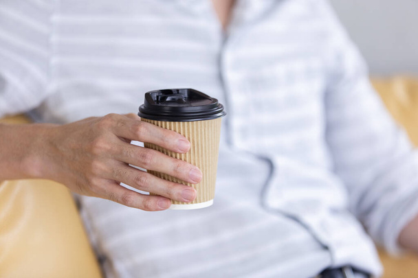 Крупним планом рука бізнесмена тримає чашку кавового паперу
. - Фото, зображення