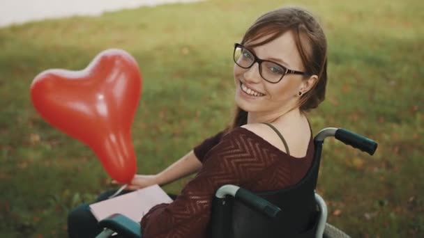 niepełnosprawny biały młody kobieta z czerwony balon korzystających jesienny bryza - Materiał filmowy, wideo
