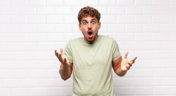 young man feeling extremely shocked and surprised, anxious and panicking, with a stressed and horrified look - 写真・画像
