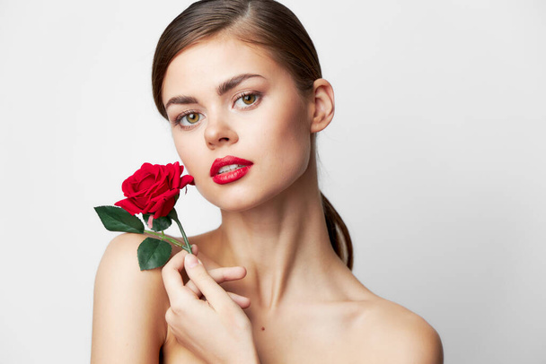 Mujer con flor hombros desnudos encanto labios rojos maquillaje brillante  - Foto, Imagen