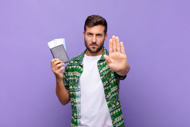 young man looking serious, stern, displeased and angry showing open palm making stop gesture. holidays concept - Foto, Imagem