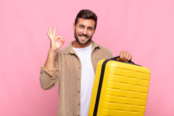 young man feeling happy, relaxed and satisfied, showing approval with okay gesture, smiling. holidays concept - Photo, image