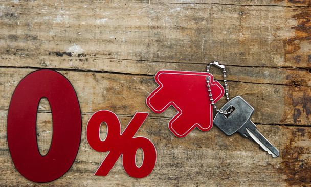 red percent sign and model house with key on wooden background . real estate concept - Photo, Image