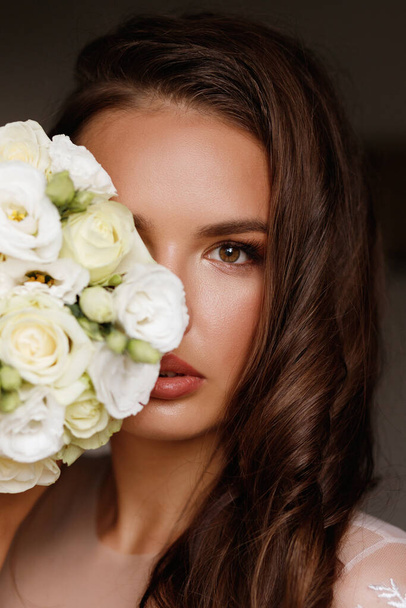 the bride covers her face with a bouquet. Wedding make-up - Photo, Image