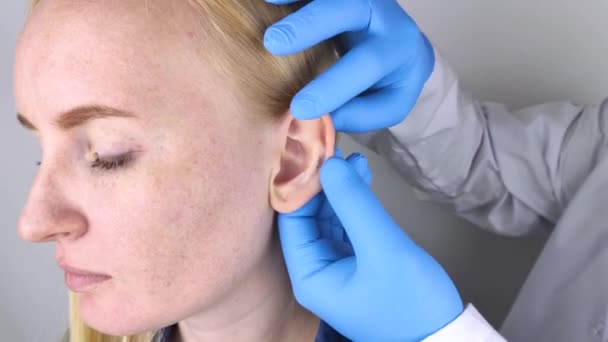 Een plastisch chirurg onderzoekt de hartkamer van een patiënt. De dokter ziet een knobbel op de krul van het oor. - Video