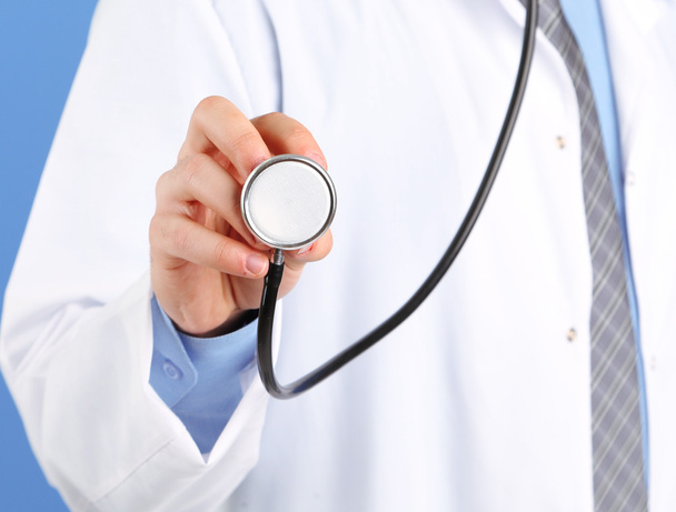 Male Doctor standing on blue background - Foto, imagen