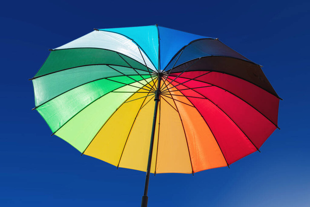 Paraguas de colores del arco iris contra el fondo azul del cielo, día soleado. Orgullo gay, símbolo de libertad - Foto, imagen