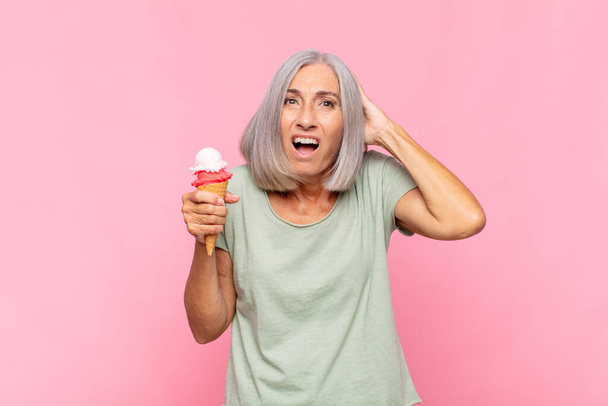 middle age woman feeling stressed, worried, anxious or scared, with hands on head, panicking at mistake having an ice cream - Fotoğraf, Görsel