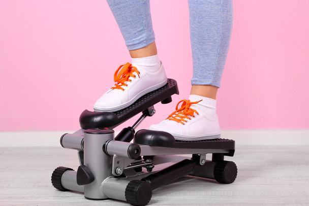 Woman doing exercise on stepper. Close-up on legs.  - Foto, afbeelding