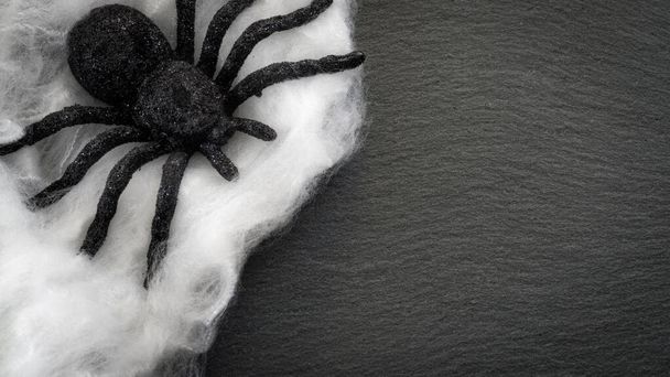 arachnophobie et halloween concept avec une araignée recouverte de toile d'araignée sur un fond gris foncé rocheux avec espace de copie et un cadre créé par le bord de la toile d'araignée et le fond noir - Photo, image