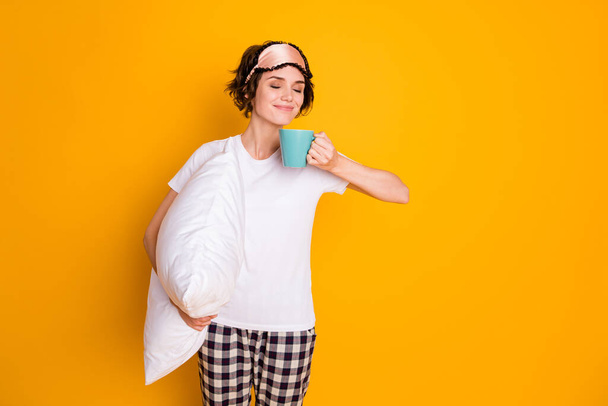 Portrait of her she nice attractive lovely pretty dreamy cheery brown-haired girl holding in hands pillow drinking warm milk isolated on bright vivid shine vibrant yellow color background - Foto, Imagen