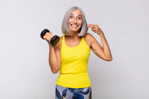 middle age woman smiling confidently pointing to own broad smile, positive, relaxed, satisfied attitude. fitness concept - Photo, image