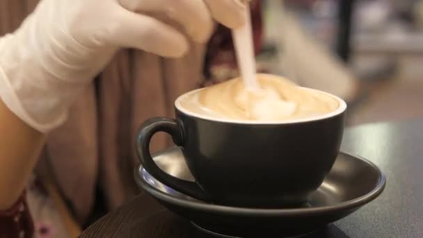  vrouwen hand in beschermende handschoenen roeren koffie met lepel. - Video