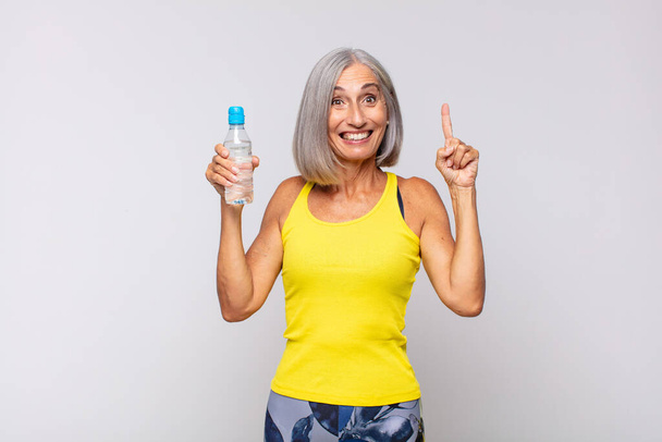 middle age woman feeling like a happy and excited genius after realizing an idea, cheerfully raising finger, eureka!. fitness concept - Valokuva, kuva