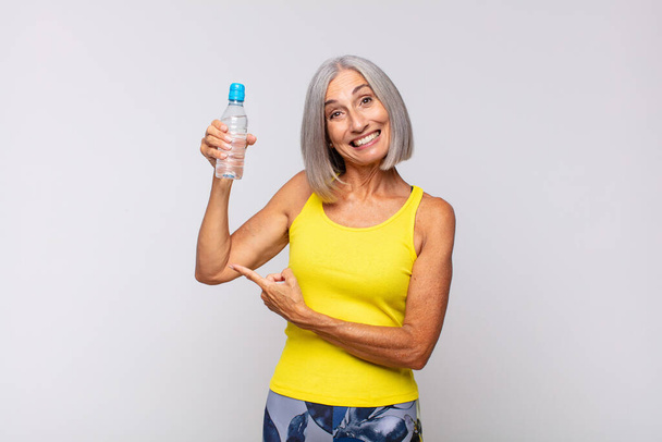 middle age woman looking excited and surprised pointing to the side and upwards to copy space. fitness concept - Fotoğraf, Görsel