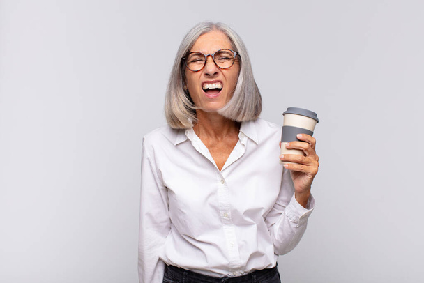 mujer de mediana edad gritando agresivamente, mirando muy enojado, frustrado, indignado o molesto, gritando sin concepto de café - Foto, Imagen